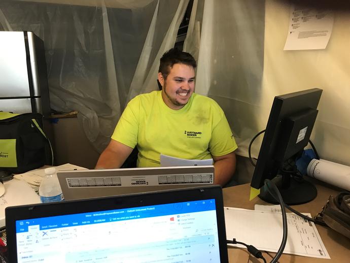 male employee in workshop smiling at computer screen