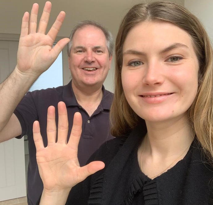 man and woman smiling at camera holding hands up