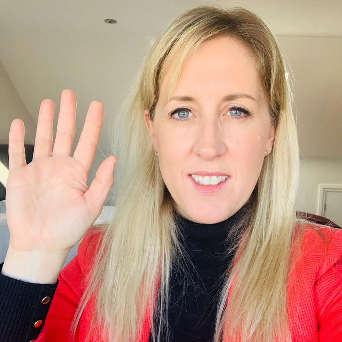 female smiling at camera holding hand in air