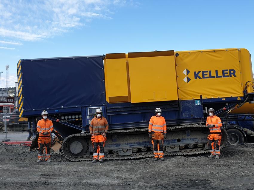 four keller employees in orange clothing in front of equipment