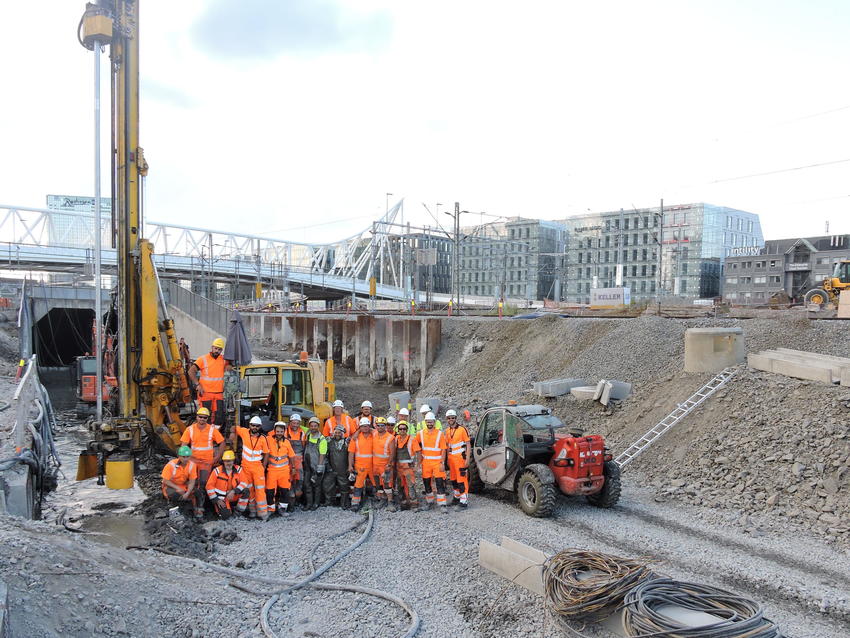 team of workers in front of rig in excavated site