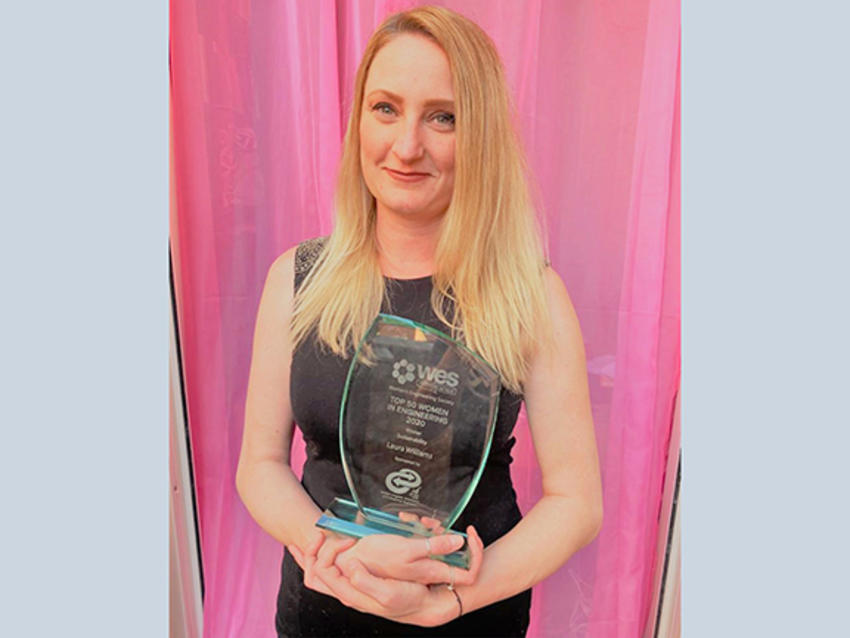 female keller employee holding glass award in front of pink background