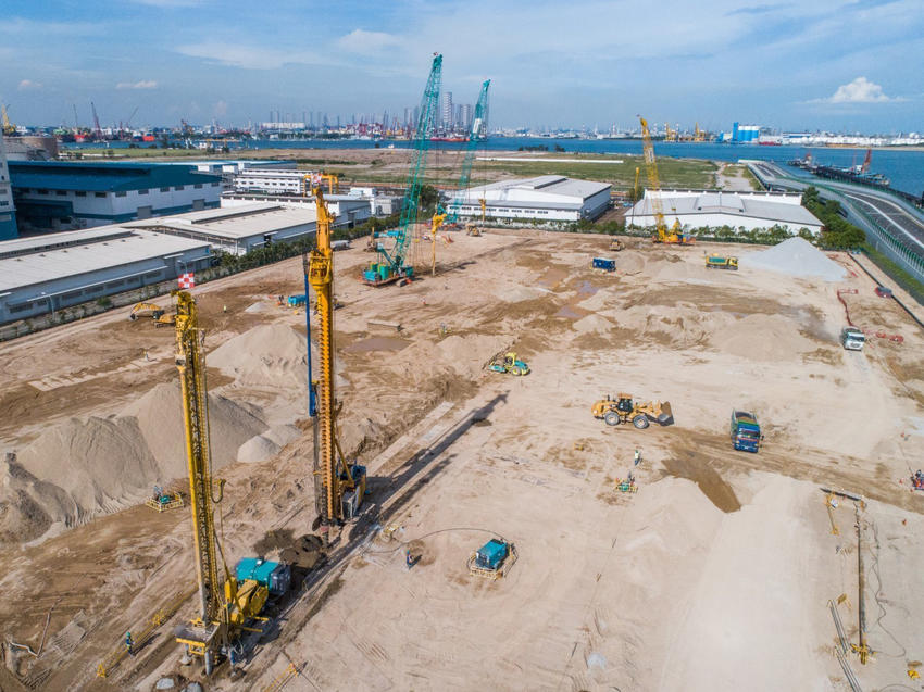 yellow and blue rigs on construction site next to water