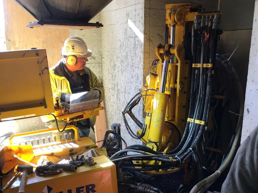 employee wearing hard hat and ear defenders working in tight space