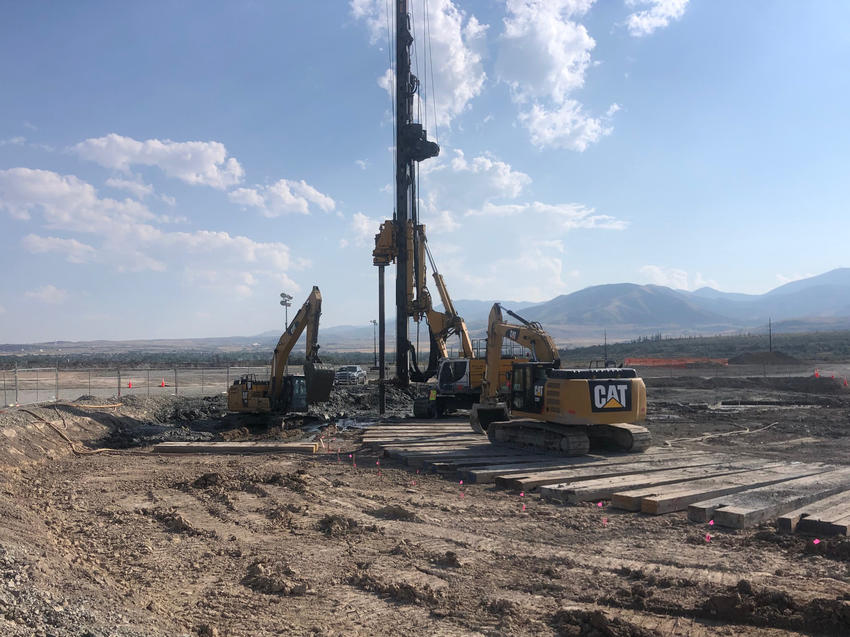 yellow rig working on construction site in front of mountains