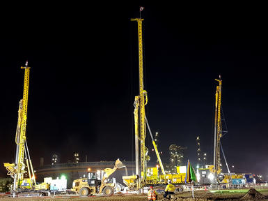 three yellow keller rigs working at night on construction site