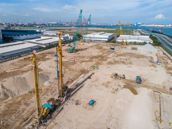 yellow and blue rigs on construction site by water