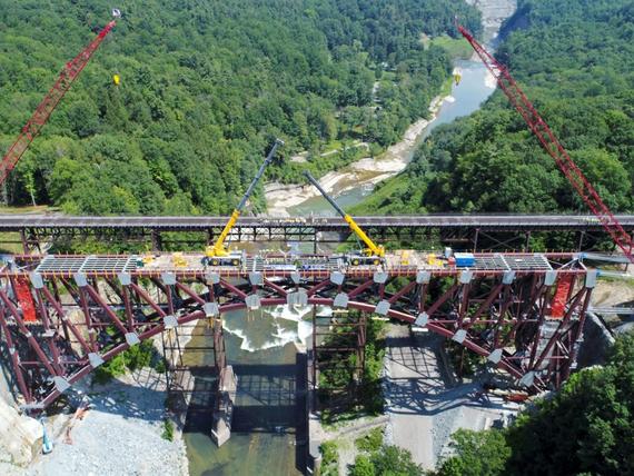 bridge under construction over river surrounded by trees