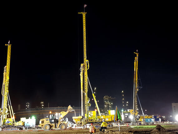 three yellow keller rigs working at night on construction site