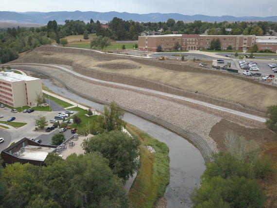 River running at the bottom of a large slope, surrounded by public buildings