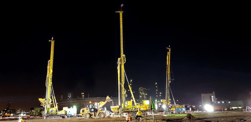 three yellow keller rigs working at night on construction site