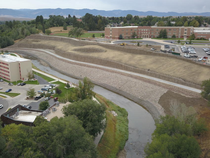 River running at the bottom of a large slope, surrounded by public buildings